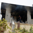 People inspect a damaged house with smoke-stained walls 