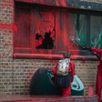 A woman smashes windows of an office building daubed with red paint