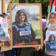 Young women hold posters and Palestinian flag