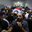 Men carry a body shrouded in a Palestinian flag on a stretcher 