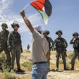 Man seen from back holds flag above line of Israeli soldiers