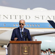 Joe Biden in sunglasses stands at a speaker's podium before Airforce 1