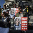 People hold posters reading "Israel killed Shireen to silence the truth" while standing in front of statue