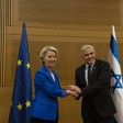 Man and woman clasp hands in front of EU and Israeli flags