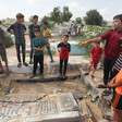 Children stand around a shattered gravestone