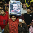 A child holds up a poster of a man as people stand behind him