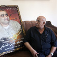 Man sits on couch next to framed poster of Mohammed El Halabi