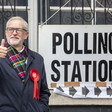 A man gives a thumbs up standing next to a polling station