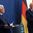 Two men stand at podiums with German and Palestinian flags