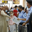 Officer holds paper while standing next to woman and young girl with other travelers in the background 