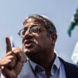 A man points with an Israeli flag behind him