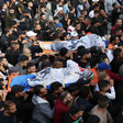 Large crowd carries two bodies on stretchers 