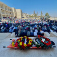 People pray before someone's corpse on a stretcher adorned with flowers 