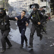 Two police officers grab a boy on each of his arms