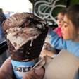 Close up of an ice cream cone with children behind it