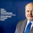 Close-up of Karim Khan viewed from chest up with ICC logo blurred out in background