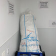 A discarded Israeli postal service bag sits in a recycling bin. Fuck is written above the word Israel, and Free Palestine is written on the top in red marker. 
