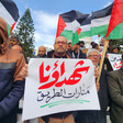 Man holds Arabic-language sign in crowd holding Palestine flags