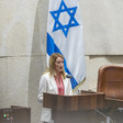 The European Parliament's president Roberta Metsola stands at a lectern with a large Israeli flag behind her