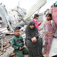 Women and children sit atop concrete rubble