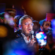 Man surrounded by demonstrators speaks into a microphone
