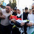 Woman holds body of toddler shrouded in Palestine flag in funeral march