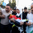 Woman holds body of toddler shrouded in Palestine flag in funeral march