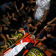 Men and boys sit next to and lean over three bodies on stretchers shrouded in Islamic Jihad and Palestine flags
