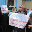 Women wearing hijabs hold Arab-language signs