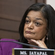 Pramila Jayapal holds her chin in her hands behind a nameplate.