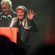 The singer Sinéad O'Connor stands in front of a microphone and waves 