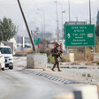 Soldier carrying rifle walks on median with Palestinian-plated cars in one lane and an empty lane on the other side