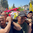 Men carry the corpse of a child on a stretcher, wrapped in flags, during his funeral 