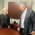 A woman and man stand next to a table and smile at eachother