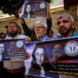 People stand shoulder to shoulder on a sidewalk carrying signs with the face of Elizabeth Tsurkov on them