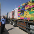Man in uniform stands next to trailer bed loaded high with boxes and crrates
