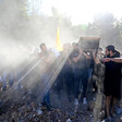 Sunlight streams over the shoulders of young men carrying a coffin