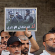 Men stand in demonstration, one of them holds a poster that says "no to administrative detention" 