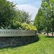 A sign with the name of the university affixed to a low stone wall.