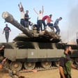 Men stand atop a smoking Israeli tank 