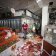 Men wearing face masks stand in aisles of supermarket covered with blood with empty refrigerator displays behind them