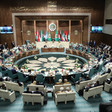 Desks are arranged in a circle in front of a number of flags at the Arab League headquarters in Cairo