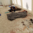 The partially covered body of a toddler lies net to the bodies of adults covered in blankets