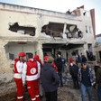 People and uniformed civic workers check the damage to a shelled house 