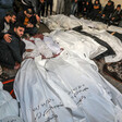 Men stand and sit around more than a dozen shrouded bodies, some of them small children