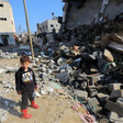 A young boy in a Star Wars sweatshirt stands next to a destroyed building