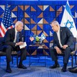 Joe Biden and Benjamin Netanyahu, both seated, lean toward each other with American and Israeli flags behind them