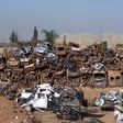 Dozens of destroyed cars and vans stacked up in an open lot
