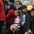 A crowd of children holding metal food containers.