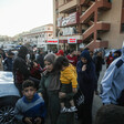 Women, men and children stand outside of hospital building